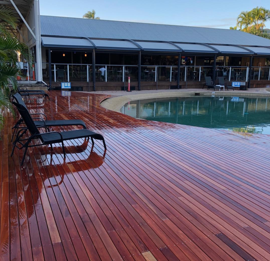 A scenic wooden deck with chairs arranged around a clear pool, creating an ideal space for relaxation and social gatherings.